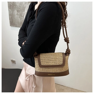 Detailed view of woven straw shoulder bag with brown leather trim and knot strap detail