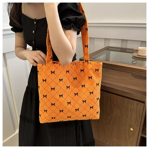 Détail du cabas en velours côtelé orange avec maille noire et petits nœuds décoratifs