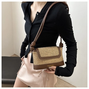 Detail shot of a woven shoulder bag with brown leather accents on a female model