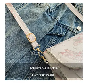 Detailed view of adjustable shoulder strap with gold metal buckle and butterfly patterns