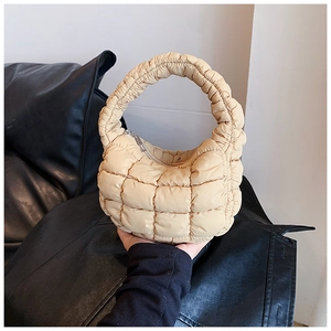 Close-up of quilted cream dumpling bag with padded texture and curved handle design