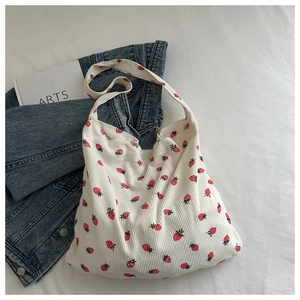 Détail d'un sac cabas en velours côtelé blanc avec motif fraise rouge et bandoulière large