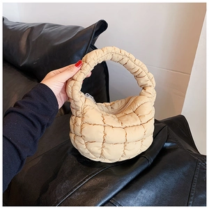 Detail of beige quilted cloud bag with puffy grid texture and silver zipper closure