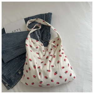Gros plan d'un sac cabas en velours côtelé blanc avec imprimé fraises rouges et texture