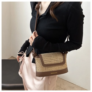 Close-up of a beige woven crossbody bag with brown leather trim and knotted strap details