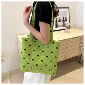 Détail du sac cabas vert clair avec nœuds noirs et texture matelassée sur le mannequin