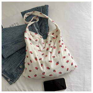 Gros plan du sac cabas en velours côtelé blanc avec motifs de fraises rouges et large bandoulière