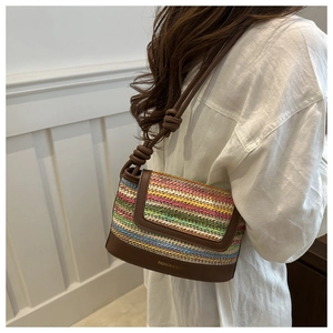 Detailed shot of multi-color woven stripe texture and brown leather strap on shoulder bag