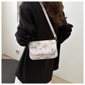 Rear view of a model wearing a beige crossbody bag with purple butterfly prints