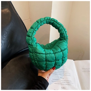 Detail of green quilted puffer handbag showing nylon fabric texture and stitching