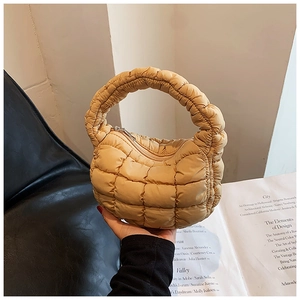 Detail of quilted puffy cloud handbag in beige with silver zipper and soft texture