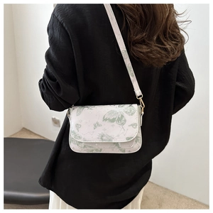 White crossbody bag with green butterfly print and gold hardware shown on model