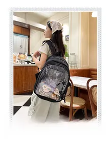 Detail of black backpack with clear PVC window showing plush dolls in cozy cafe setting