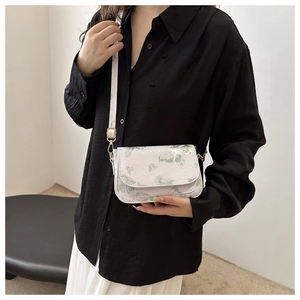 Detailed view of a white flap crossbody bag with green butterfly patterns and star prints