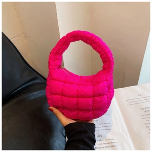 Detail of hot pink puffer handbag with quilted pattern and round integrated handle