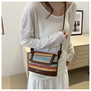 Detail of colorful striped woven crossbody bag with brown leather base and golden text logo