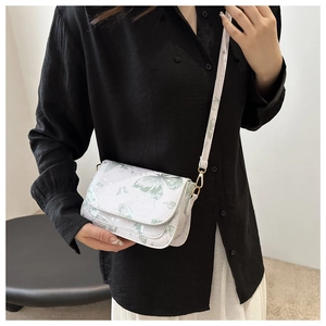 Detail of the white crossbody bag with green butterfly prints and gold metal hardware