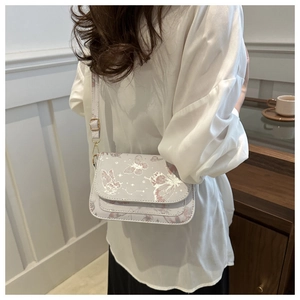 Detail view of light purple crossbody bag with butterfly prints and gold hardware
