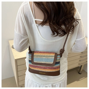 Close-up of a colorful woven crossbody bag with brown leather accents and stripe pattern