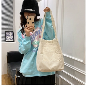 Close-up of cream corduroy tote bag with Fashion label in a casual lifestyle setting