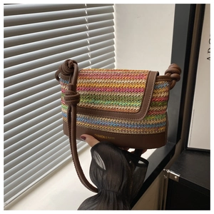Close-up of colorful woven straw bag with leather trim and gold fashion lettering