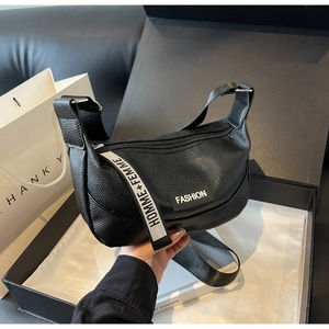 Détail du sac en cuir litchi noir avec bandoulière rayée en tissu HOMME+FEMME
