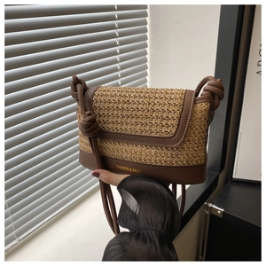 Detailed close-up of woven straw crossbody bag with leather edges and knotted strap