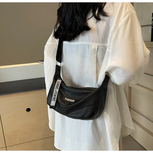 Détail du sac croissant noir texturé avec étiquette Fashion et bandoulière