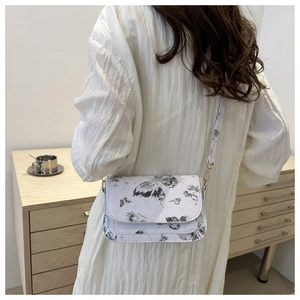 Detail showing white leather crossbody bag with butterfly patterns on a female model