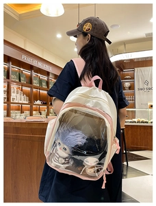 Detailed view of a pink and beige ita bag with clear window showing plush cotton dolls