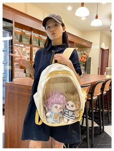 Detailed view of white and yellow Ita bag featuring transparent window for plush dolls