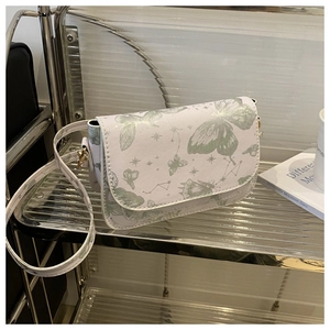 Close-up of white crossbody bag featuring green butterfly and star prints on display