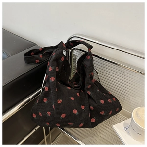 Détail d'un sac fourre-tout en velours côtelé noir à imprimé fraises sur une chaise