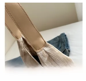 Gros plan sur la texture en daim beige et les coutures soignées de la bandoulière