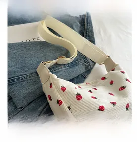 Détail du sac en velours côtelé à motif fraise avec bandoulière tissée beige