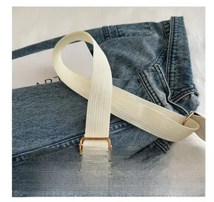 Détail de la bandoulière réglable en toile blanche avec boucle en métal doré