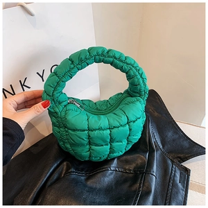 Macro shot of bright green quilted puff handbag texture with circular handle and metal zipper