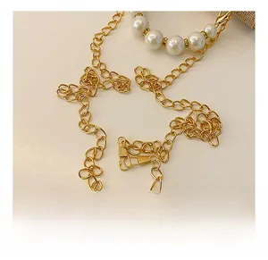 Détail de la bandoulière en chaîne dorée avec perles blanches et anneaux de strass brillants
