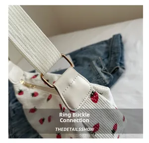 Détail de la boucle métallique sur un sac à main en velours côtelé à imprimé fraise