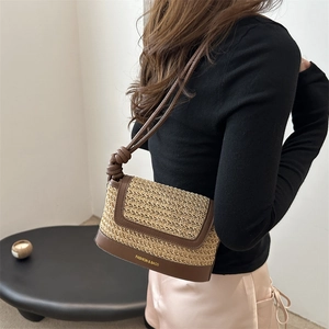 Handcrafted woven straw shoulder bag with dark brown trim and knot strap detail for summer