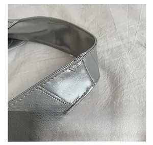 Close-up of bright silver metallic handle and refined stitching on minimalist handbag
