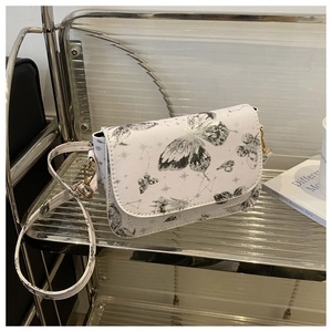 Detail of white square bag with butterfly prints, celestial patterns, and gold hardware