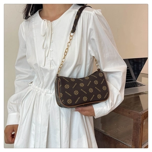 Gros plan du sac demi-lune marron vintage avec monogramme et bandoulière en chaîne dorée