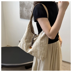 Détail d'un sac beige avec motifs de feuilles blanches et perle ambrée