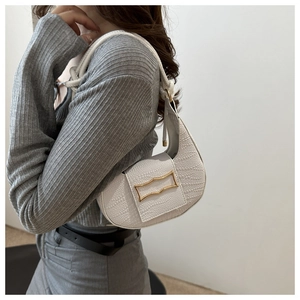 Detail of white crocodile pattern hobo bag with a gold metal buckle on shoulder