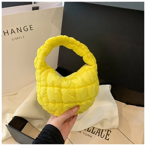 Detail of a bright yellow quilted cloud bag featuring nylon texture and a top zipper