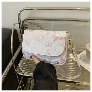 Detail of white crossbody bag with pink butterfly patterns and golden metal hardware