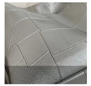 Detail view of premium lychee grain leather texture and precise stitching on gray crossbody bag