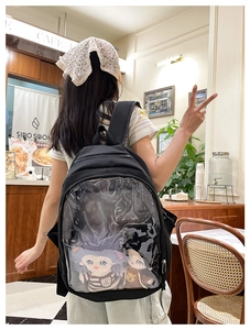 Detail of black ita-bag with large transparent window showing cute plush dolls inside