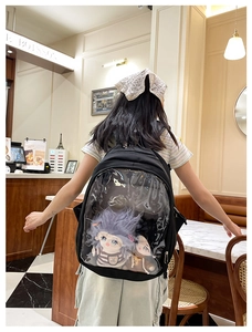 Close-up of a black Ita-bag with clear PVC window showcasing two plush cotton dolls inside